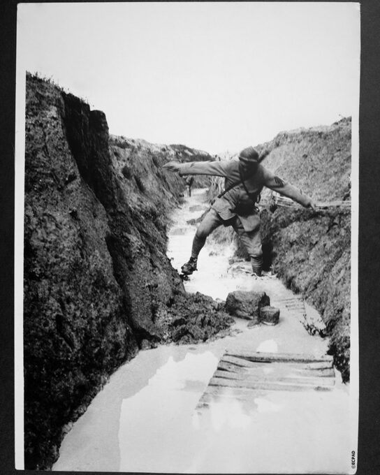 Un agent de liaison traverse avec difficulté un boyau inondé Loys Roux 5.07.1917 ©ECPAD